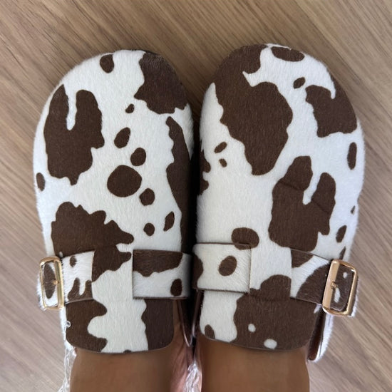 Mules em imitação de pele de vaca com fivela dourada